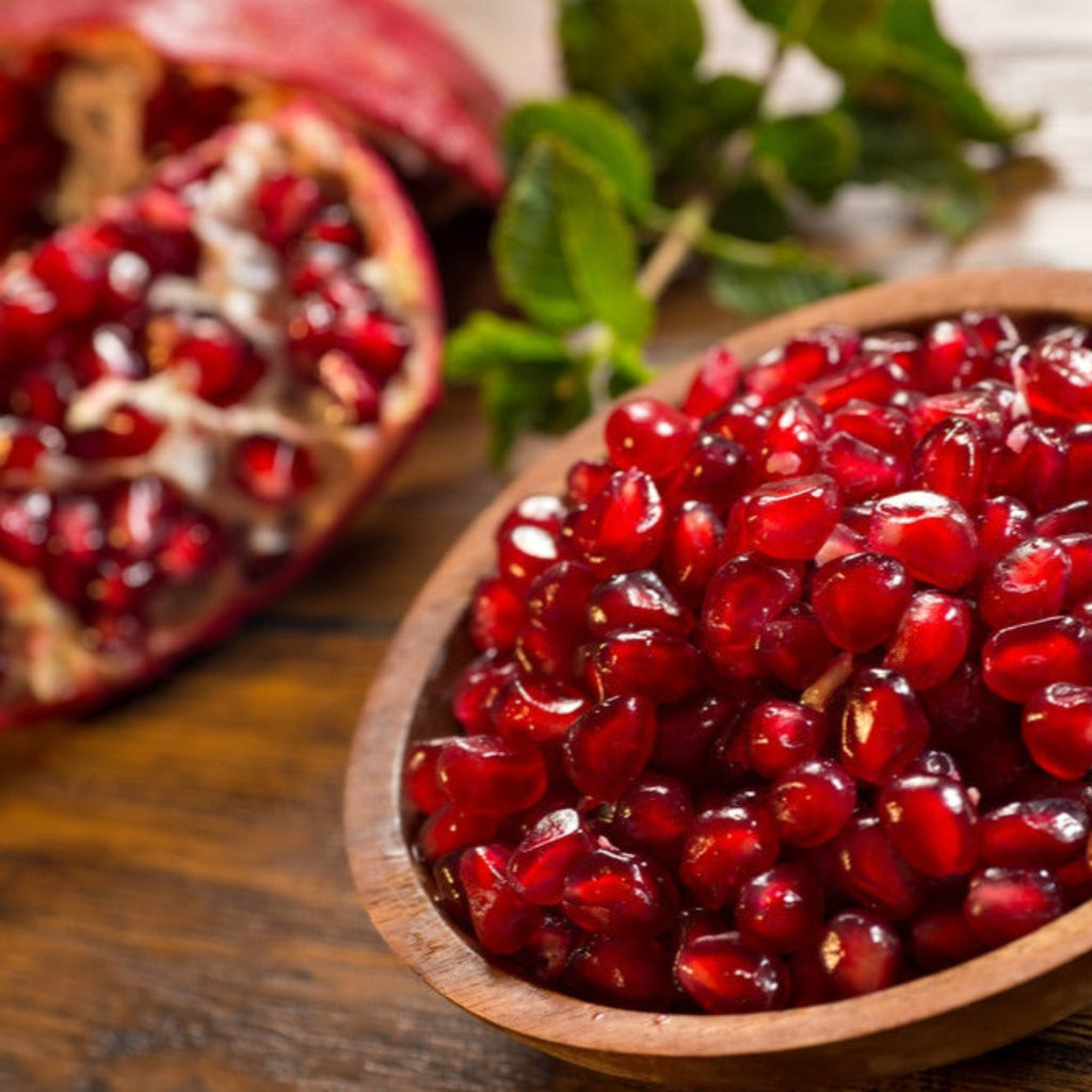 Large red pomegranates hanging on a leafy branch (view 6)